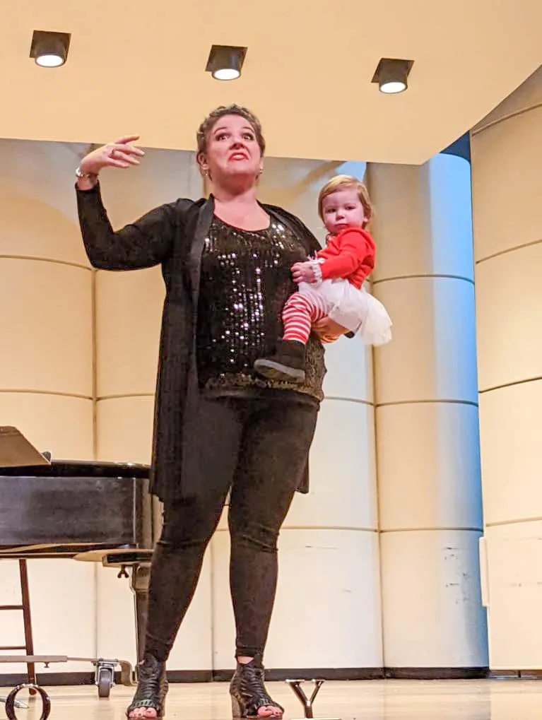 Jessica Doyle-Mekkes speaking on stage while holding her daughter.